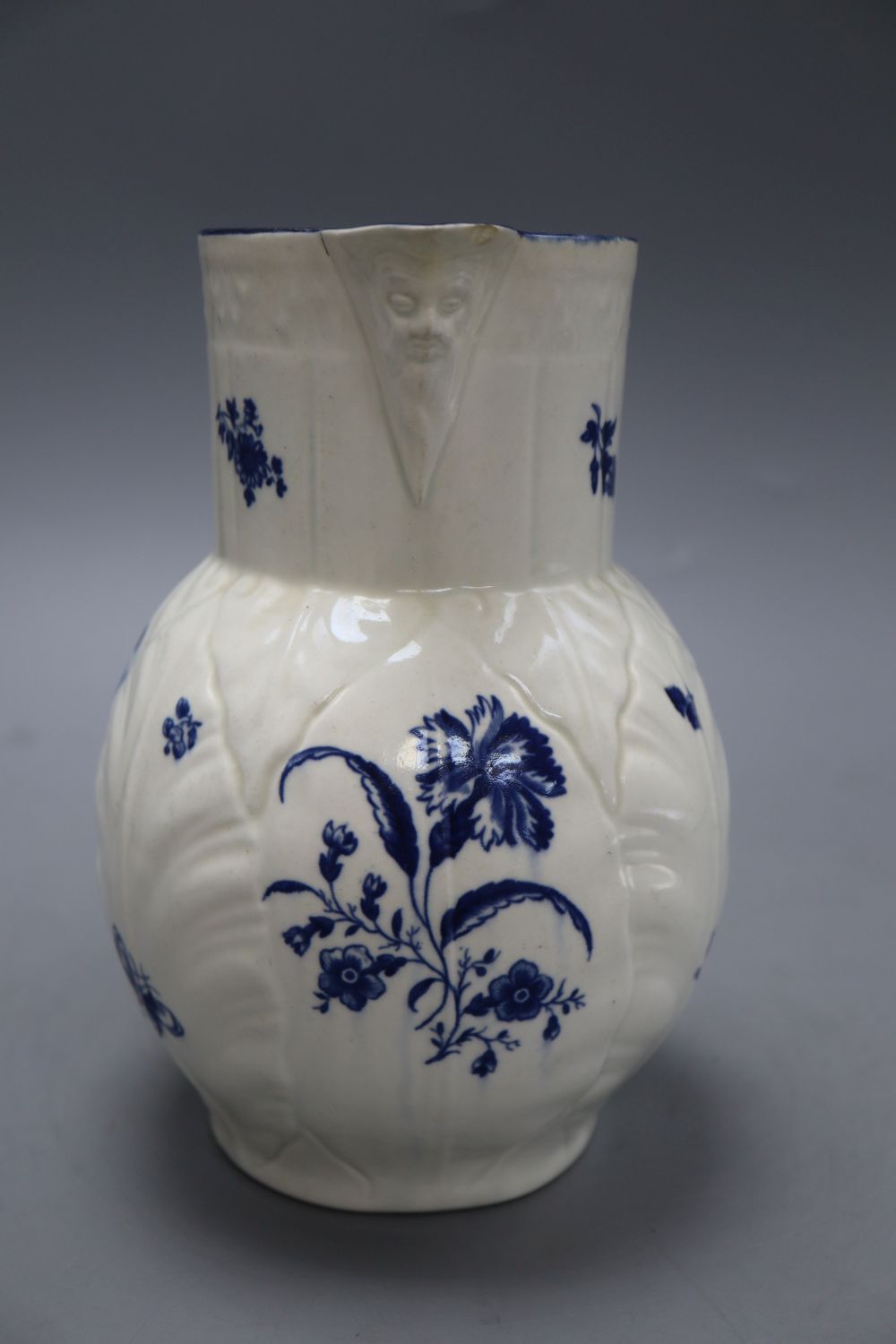 A Caughley cabbage leaf mask jug, c.1780, with scroll handle, decorated with floral sprays in underglaze blue, crescent mark, height